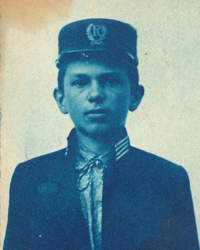 Chłopiec w mundurku, fotografia w odcieniach niebieskiego. 