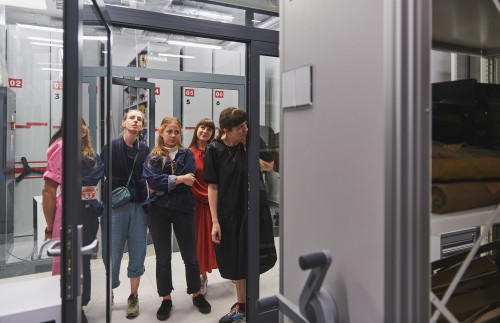 Grupa ludzi zwiedzająca magazyn. 